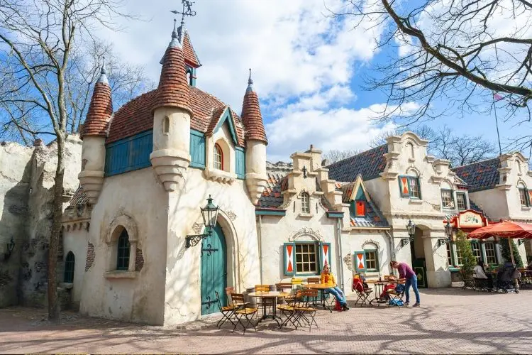 Ambiente lúdico no parque Efteling com mesas e pessoas sentadas