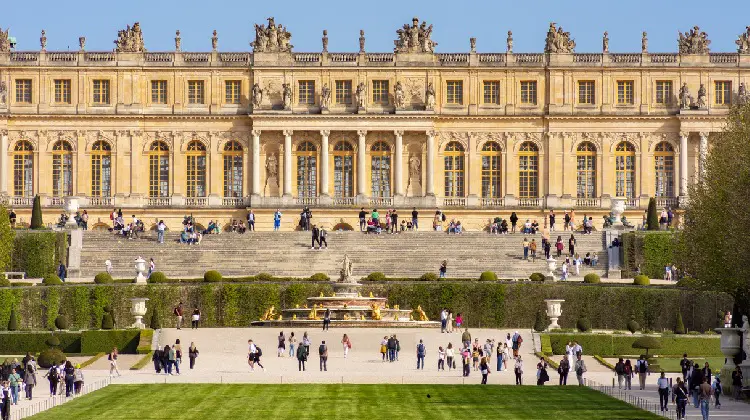 Turistas com ingresso Palácio de Versalhes.
