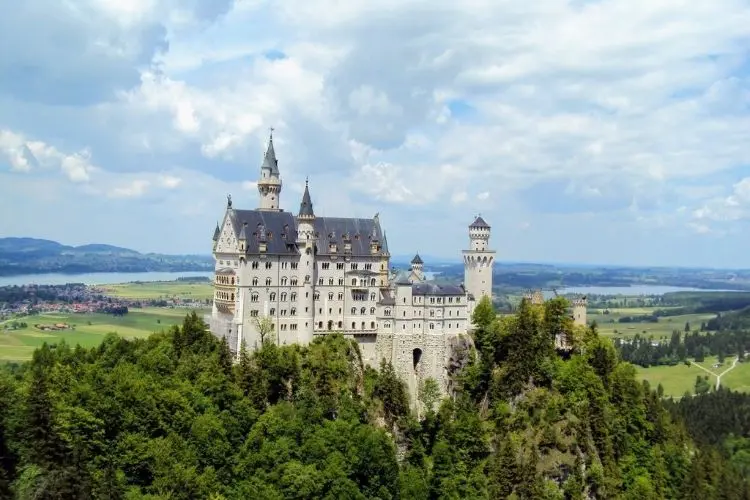 Vista do castelo de Neuschwanstein no topo de colina com floresta em volta