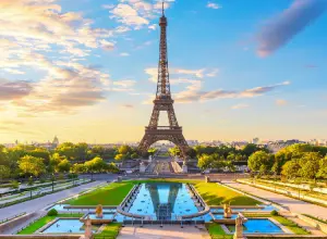 Torre Eiffel em dia de sol, com seu reflexo em lago.