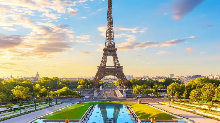 Torre Eiffel em dia de sol, com seu reflexo em lago.